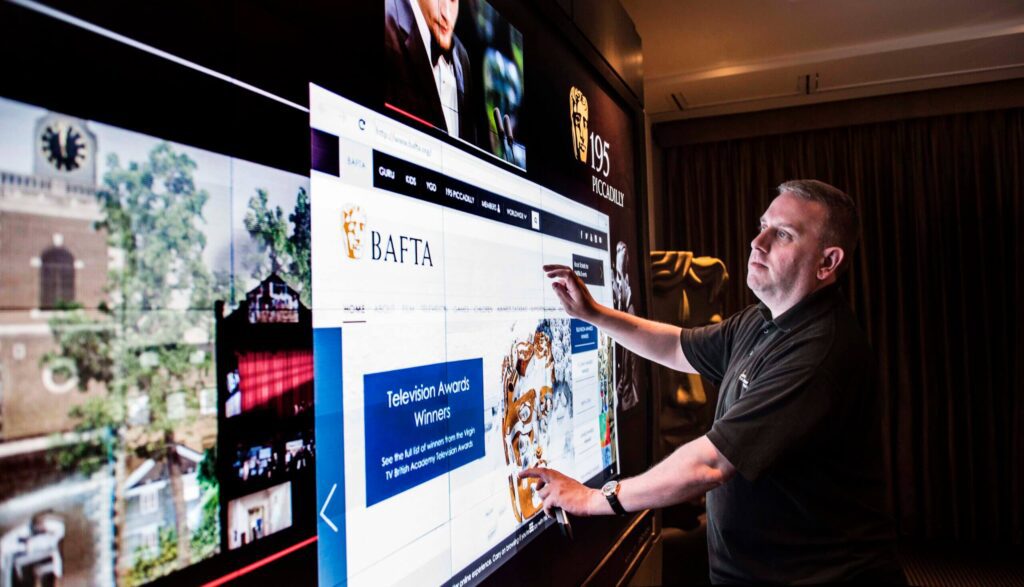 White Light staff member using a large interactive LED display screen, demonstrating digital signage and event technology solutions in a professional indoor setting.