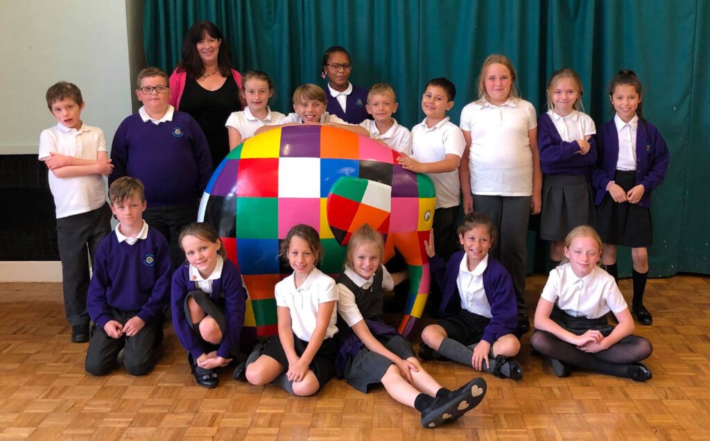 Schoolchildren posing with a colourful Elmer elephant sculpture supporting the Heart of Kent Hospice partnership.