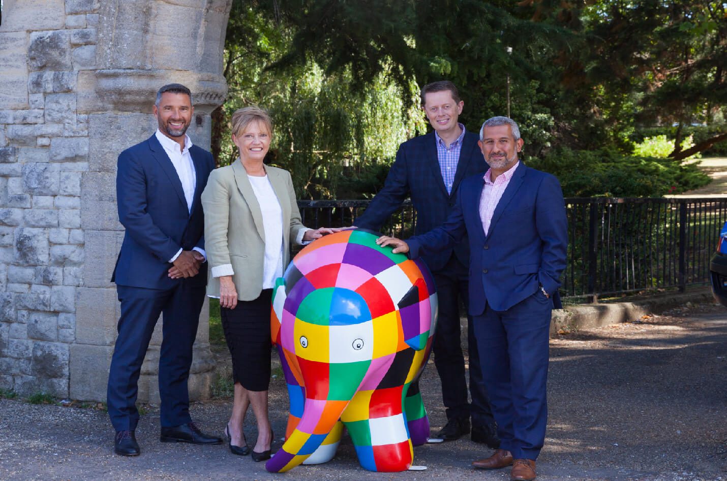 Business leaders posing with a colourful Elmer elephant sculpture during Elmer’s Big Heart of Kent Parade in support of Heart of Kent Hospice.