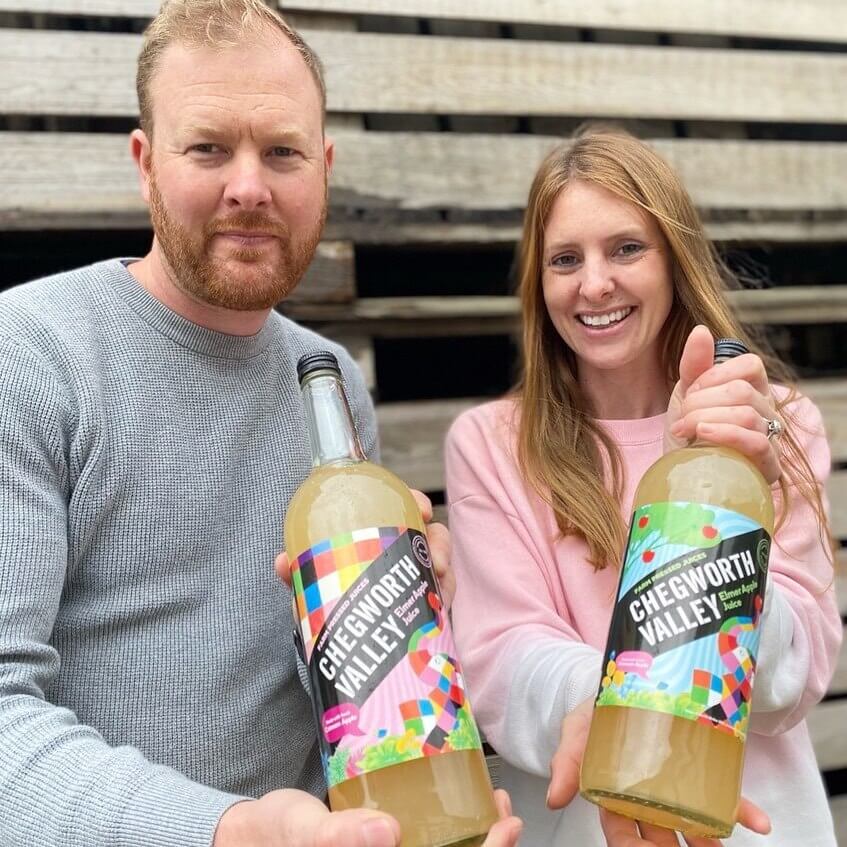 Two people holding Chegworth Valley Elmer apple juice bottles supporting the Heart of Kent Hospice partnership.