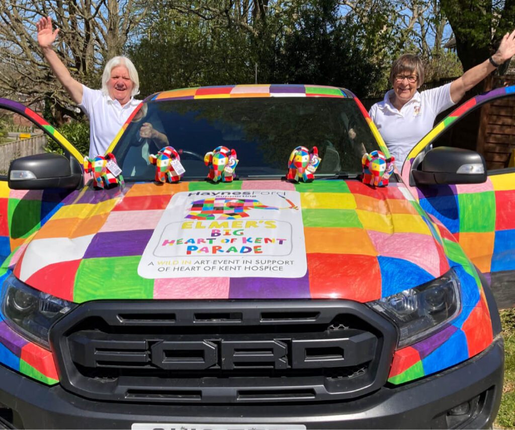 Elmer the Elephant–themed branded car wrapped in colourful patchwork for the Heart of Kent Hospice Elmer’s Big Heart of Kent Parade, with charity supporters celebrating.