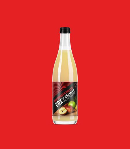 Chegworth Valley Cox & Bramley apple juice bottle, branded glass packaging, farm-pressed English apple juice on red background.
