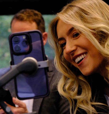 Ellie, a content creator, smiling while recording content on a smartphone mounted on a handheld stabiliser.