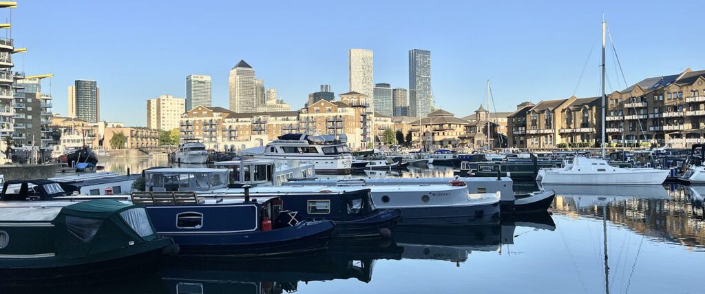 Limehouse marina, lots of barges on the water, with a view of the London skyline in the background.